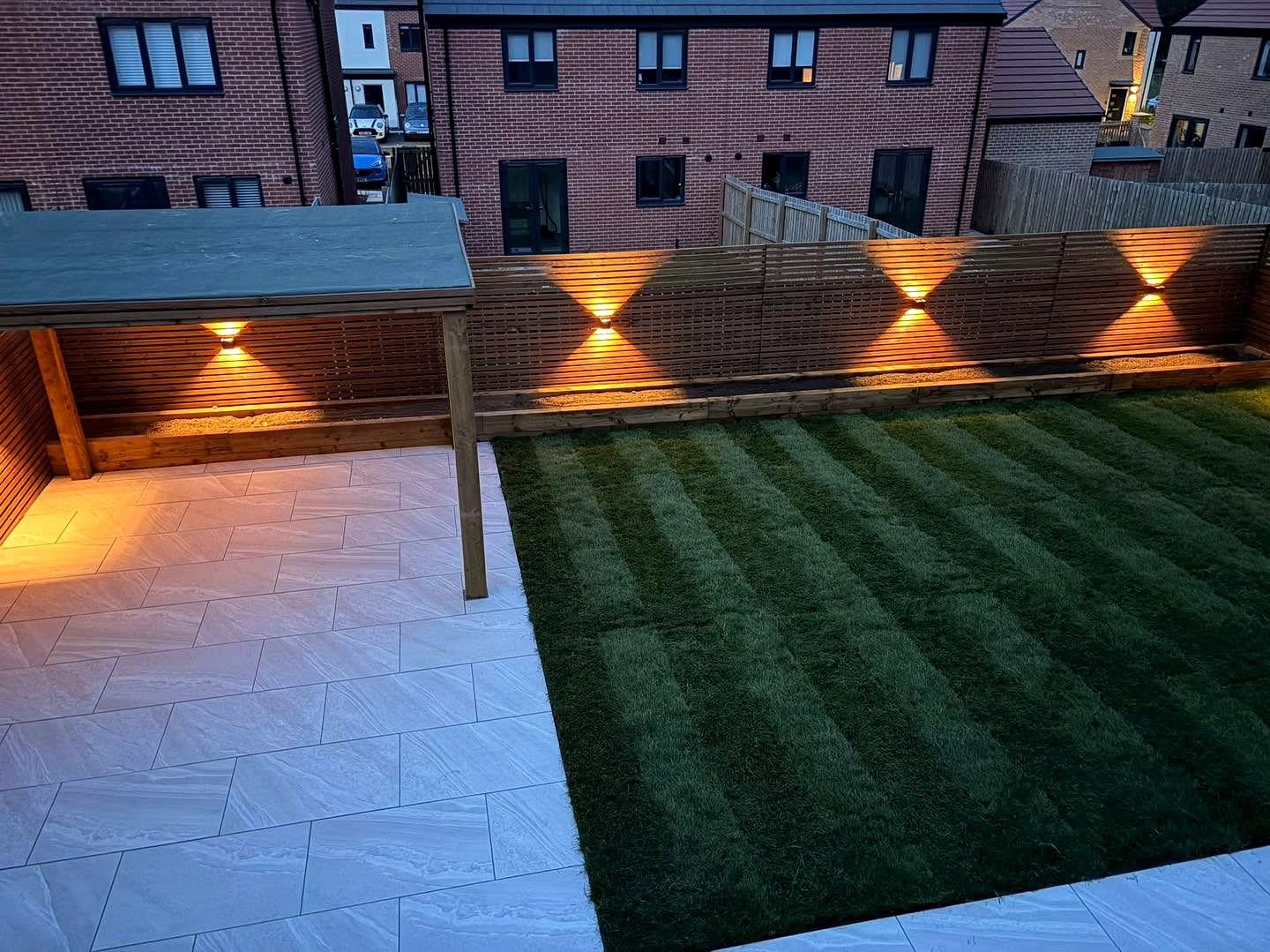 Fence and pergola downlights in a garden at dusk.